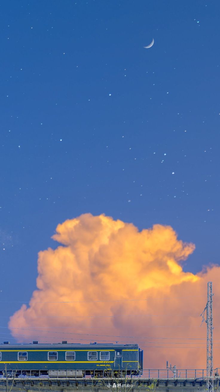 A glowing orange cloud above a train passing through a city at dusk.