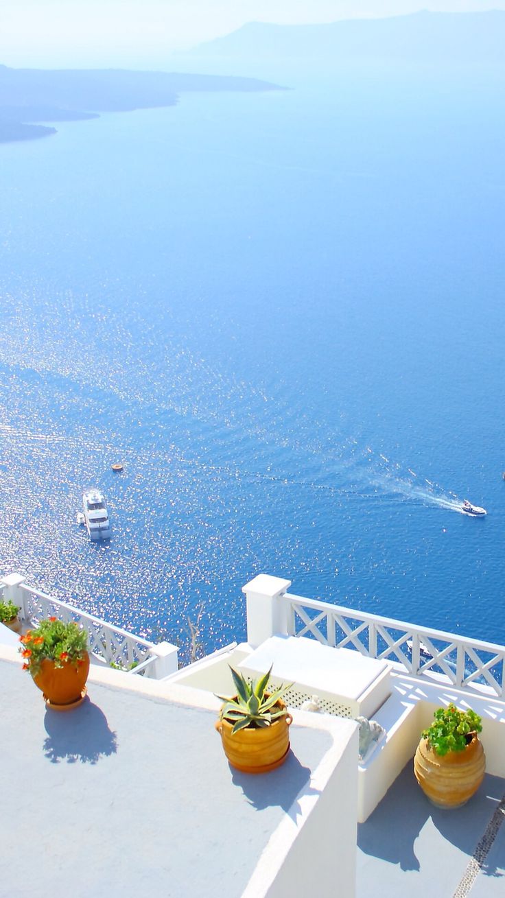 Whitewashed terraces with potted plants overlooking the deep blue sea.