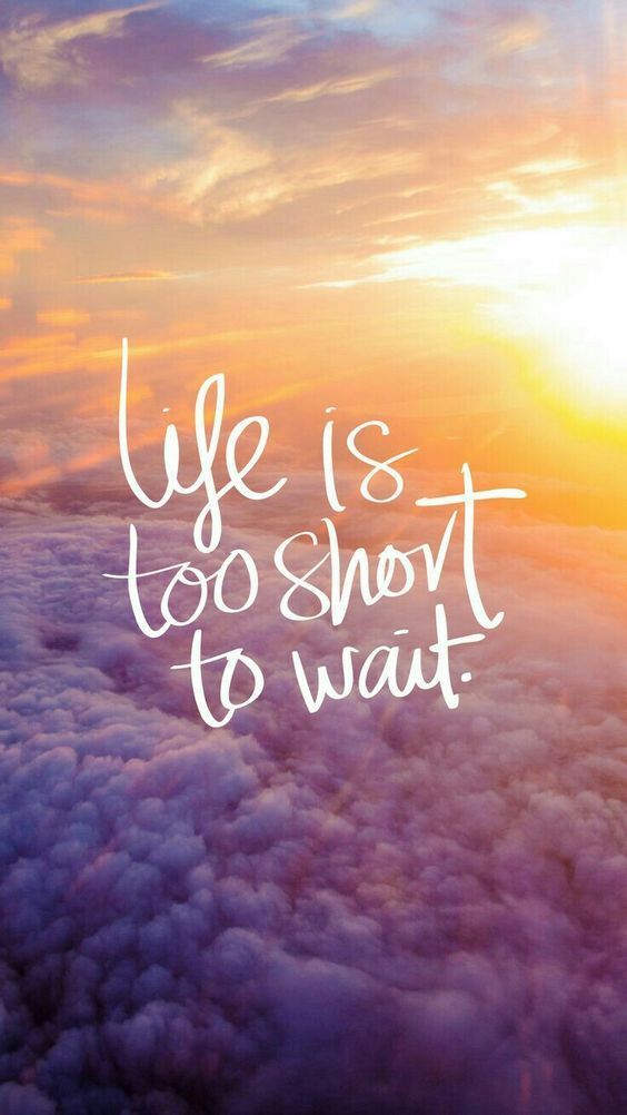 "Life is too short to wait" in white script over a sunset above purple clouds.