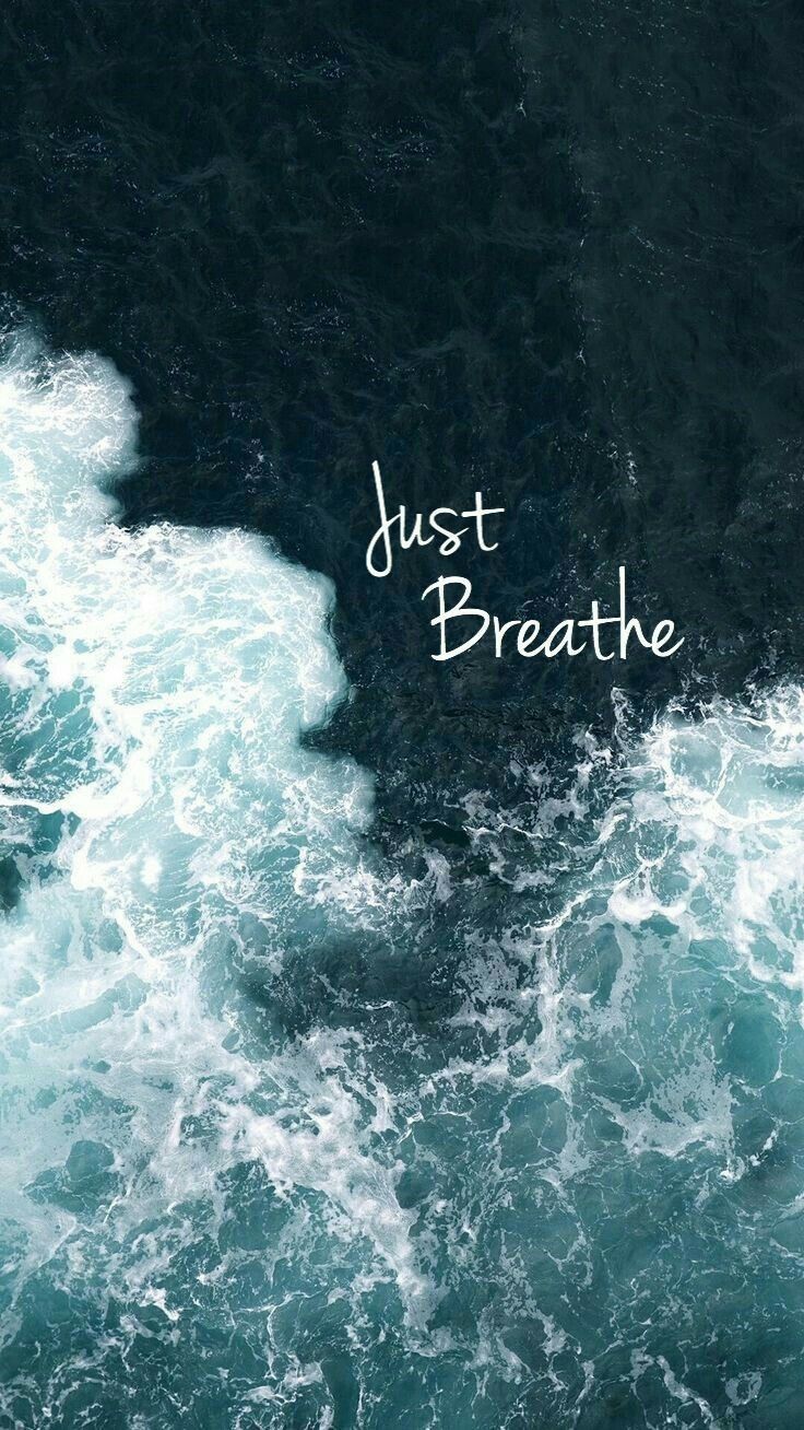 "Just breathe" in white script over crashing white waves on dark green water.