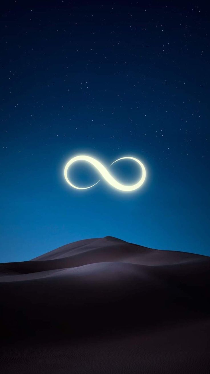 A glowing infinity symbol above dark sand dunes under a deep blue sky.