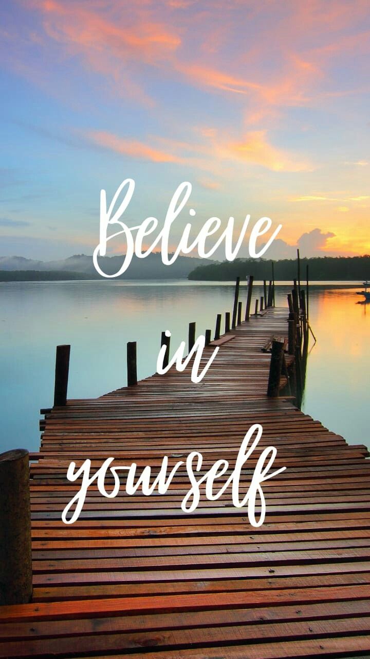 "Believe in yourself" in white script over a wooden pier at sunset.