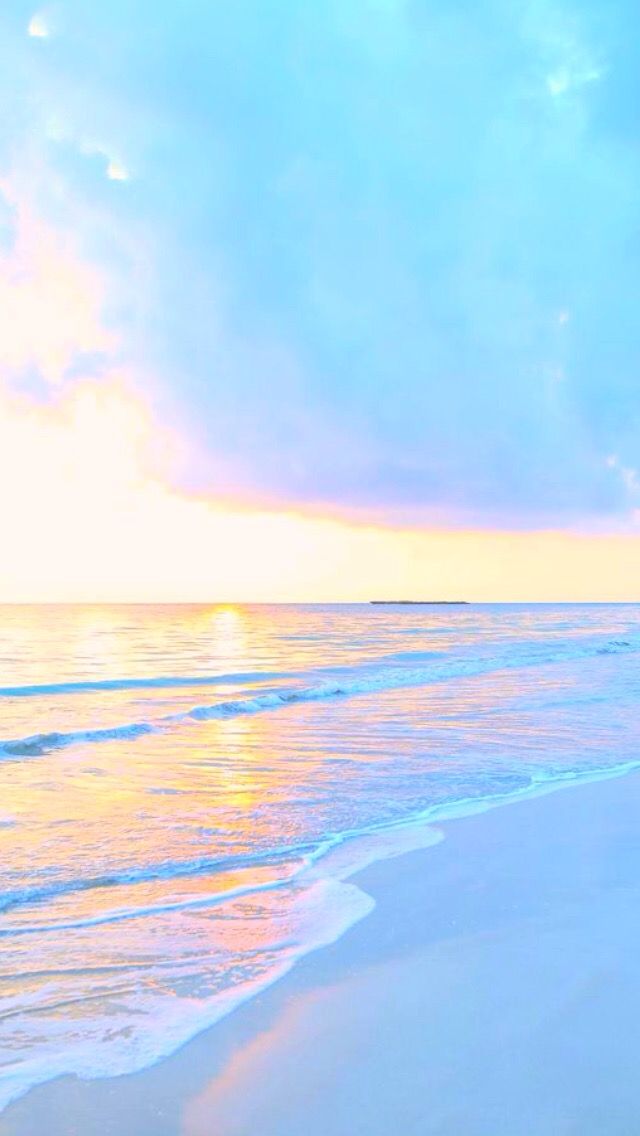 Soft waves washing onto a pastel beach under a peach and blue sky.