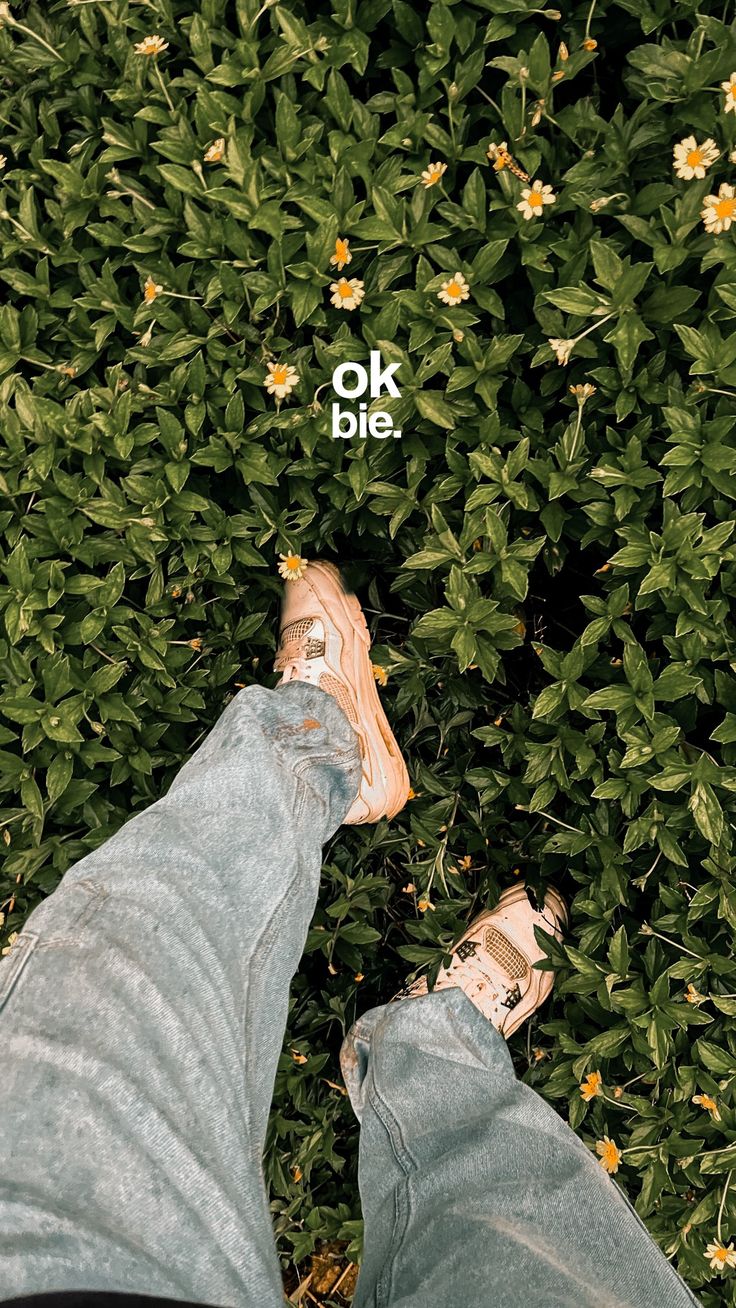 Legs in grey jeans stretched out on green grass, with a small "OK" in white.