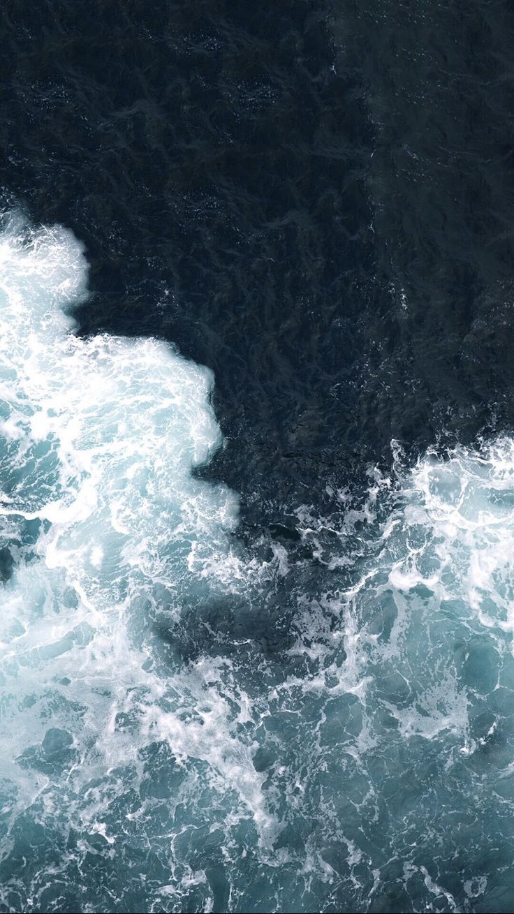White waves crashing against dark rocks.