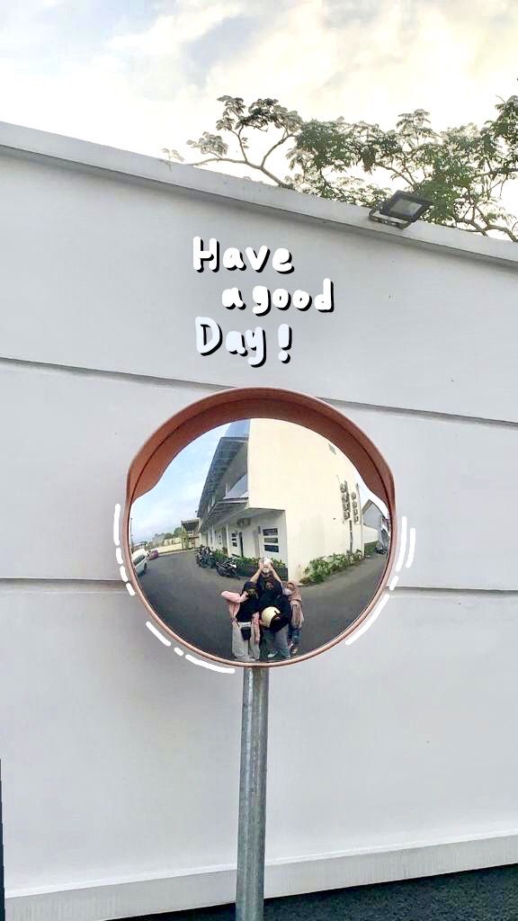 "Have a good day!" written on a white wall above a round convex traffic mirror.