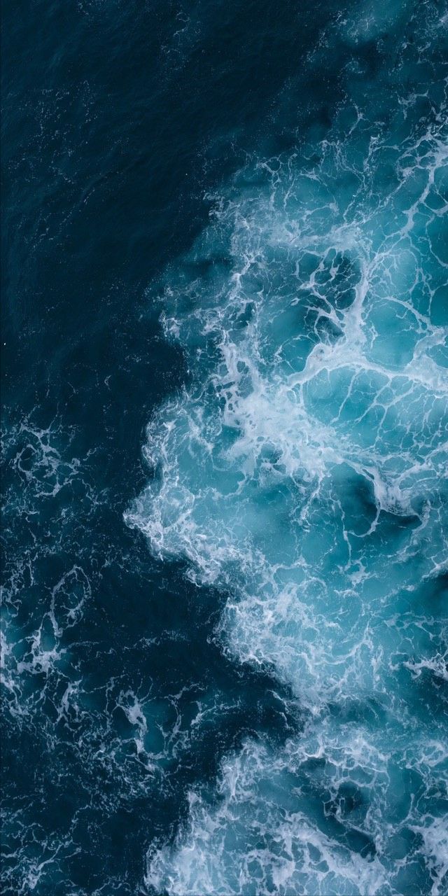 Deep blue ocean waves breaking into white foam, seen from directly above.