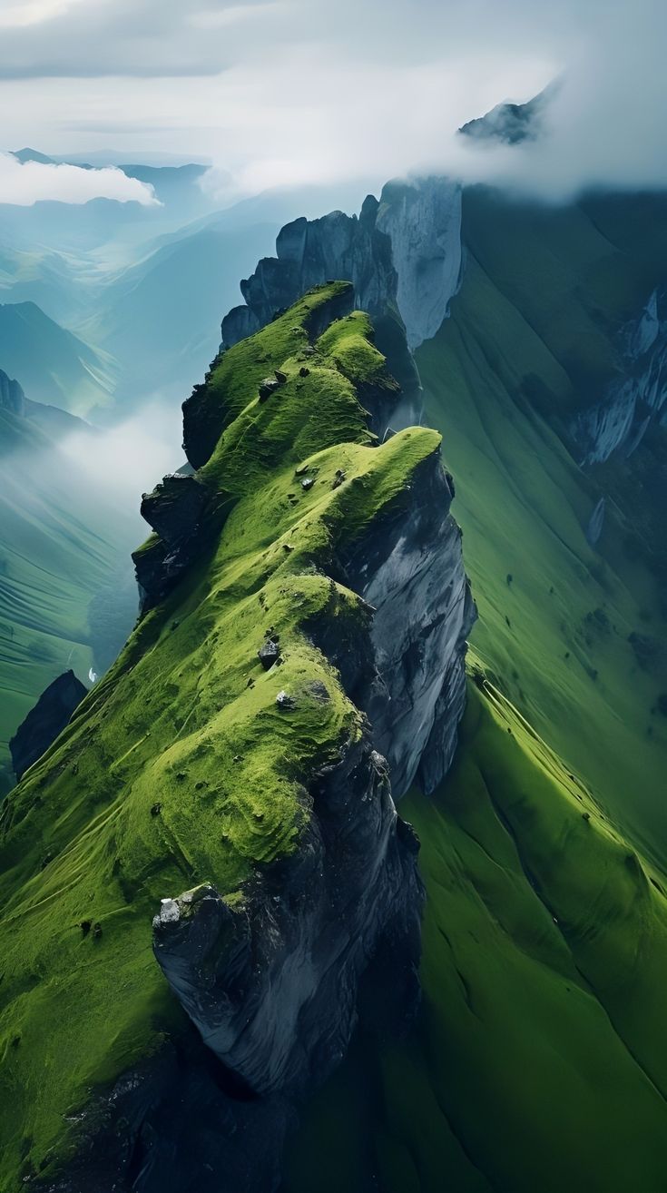 A narrow green mountain ridge dropping into misty valleys.