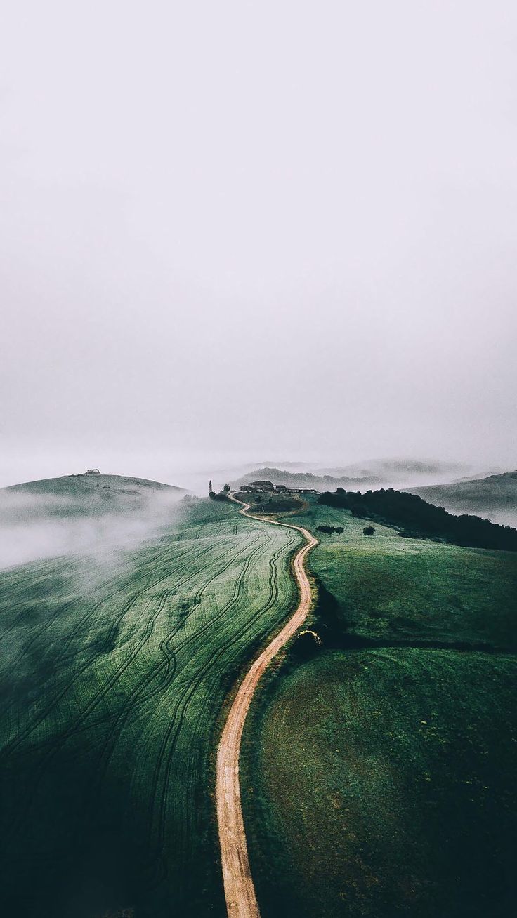 A narrow path winding across a misty green hilltop.