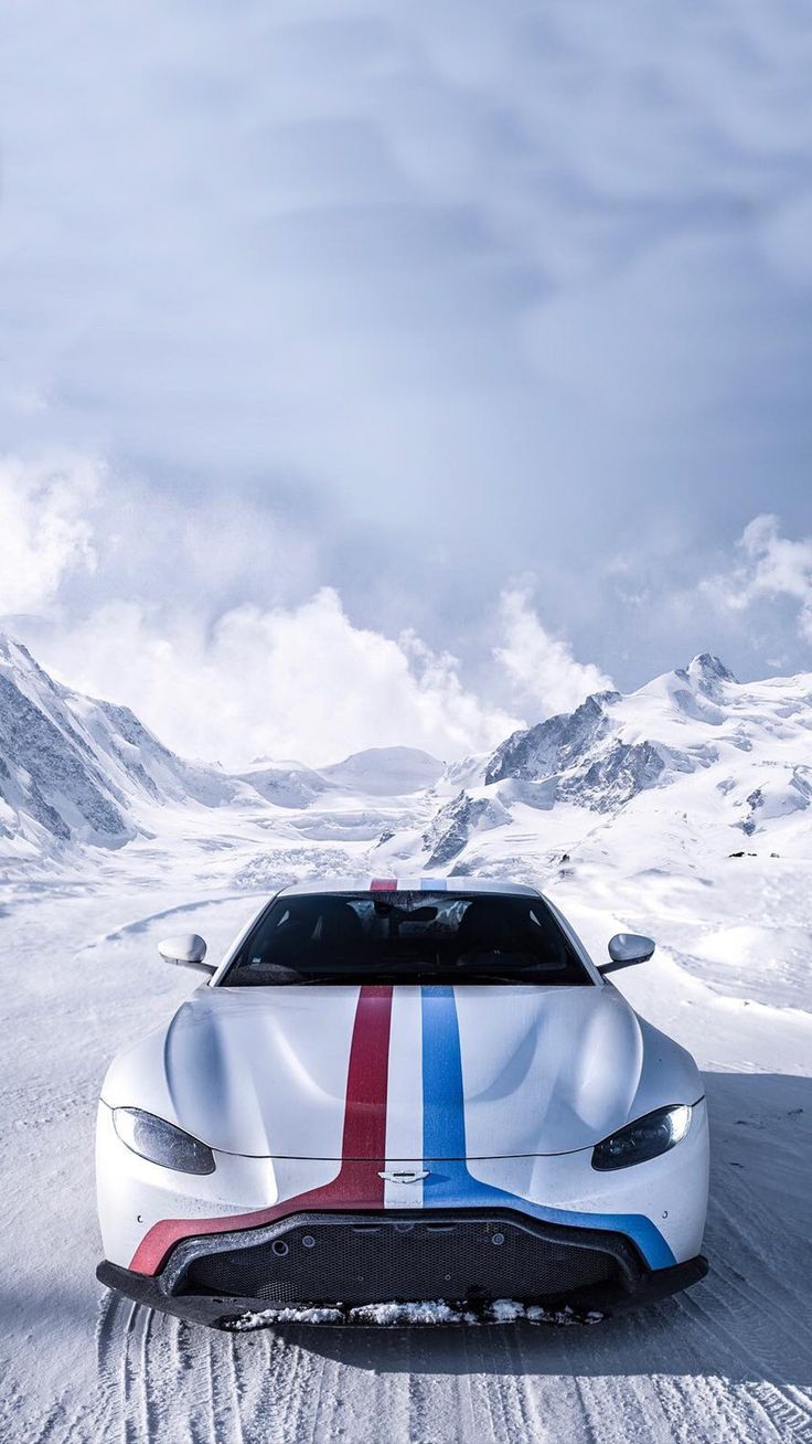 A white sports car with red and blue racing stripes on a snowy mountain road.