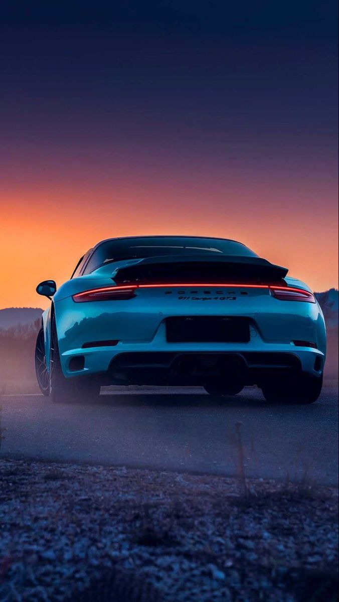 A blue Porsche Panamera seen from behind on a road at sunset.