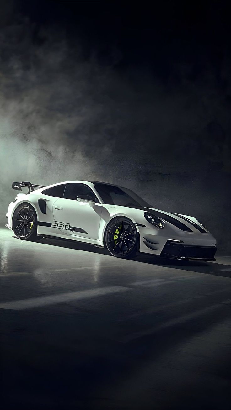 A white Porsche 911 GT3 RS in dark, smoky studio light.