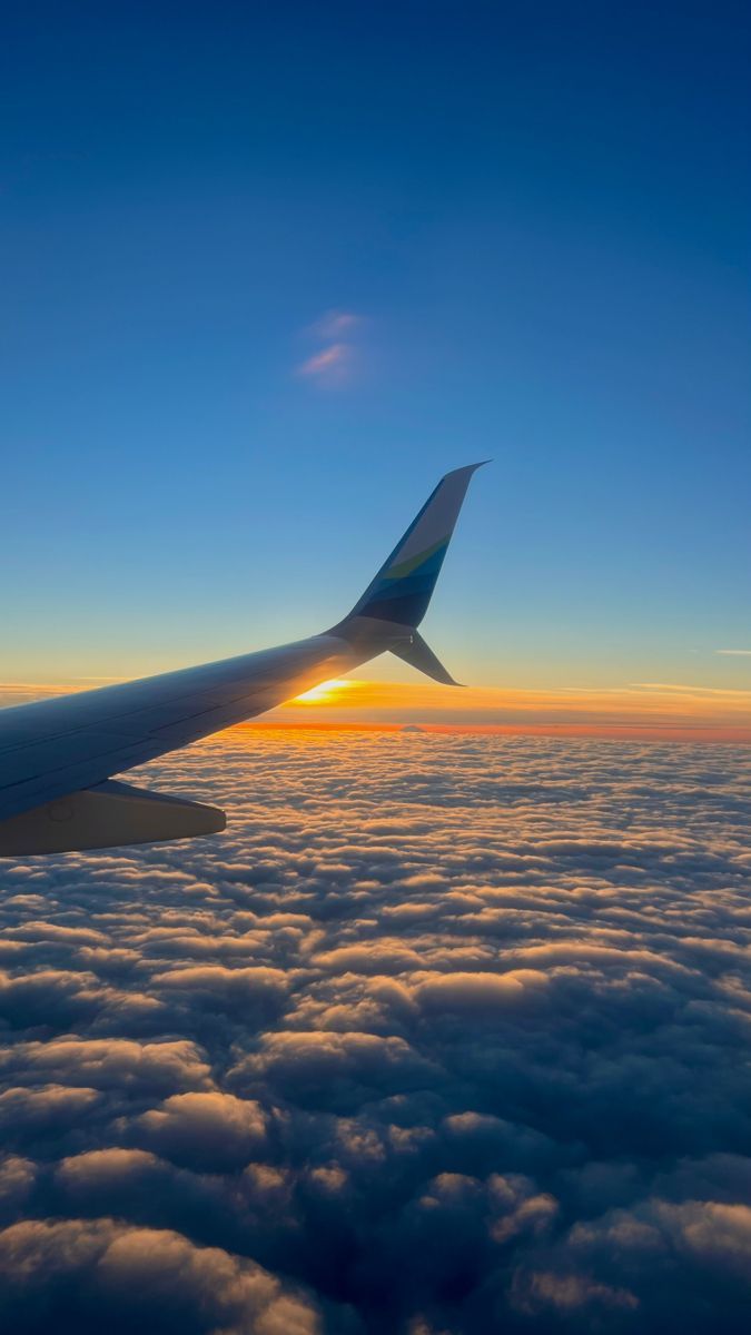 An aeroplane wing over a sea of clouds at sunset, seen from the window.